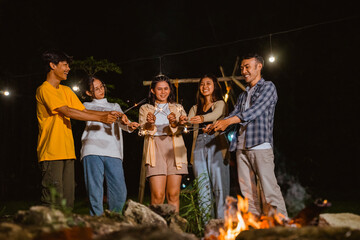 a group of people playing with the fireworks and smile while camping at the camp site