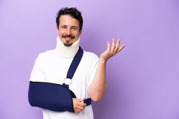 Young caucasian man wearing a sling and neck brace isolated on purple background extending hands to the side for inviting to come