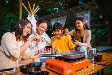 the group of people eating grilled beef together using several eating stuff at the camp site