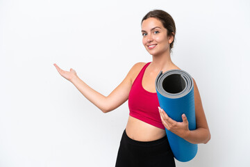 Young sport caucasian woman going to yoga classes while holding a mat isolated on white background...