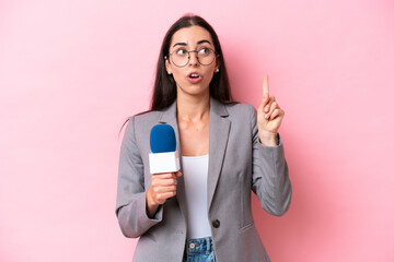 Young caucasian tv presenter woman isolated on pink background thinking an idea pointing the finger...