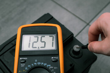 Check and charge car battery with charger. Auto mechanic measures voltage. Voltmeter to check...
