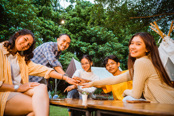 a group of people high fived happily while hangout together at the camp site