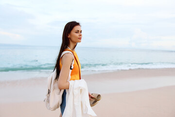 Fototapeta na wymiar Young woman with a backpack walks on the beach, summer vacation on an island by the ocean in Bali