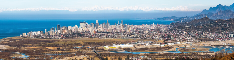 Fototapeta na wymiar Panoramic view of Batumi city in Georgia. Landscape from the top, against the background of the mountain and the Caucasus Range and Elbrus. Spring. Skyscrapers. Adjara region. Black Sea and tourism