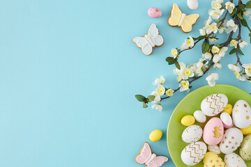 Easter decoration concept. Top view photo of green plate with colorful easter eggs butterfly shaped...