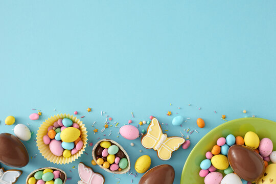 Easter sweets concept. Top view photo of green plate with chocolate easter eggs with dragees gingerbread and sprinkles on isolated pastel blue background with empty space