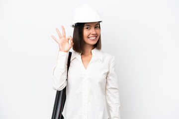 Young architect woman with helmet and holding blueprints isolated on white background showing ok sign with fingers