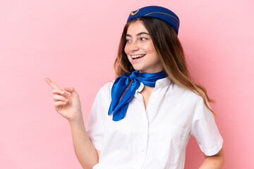 Airplane stewardess caucasian woman isolated on pink background pointing finger to the side and presenting a product