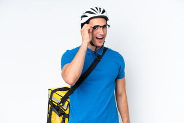 Young caucasian man with thermal backpack isolated on white background with glasses and surprised