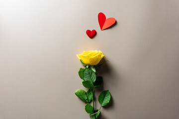 Eine einzelne gelbe Rose mit roten Herzen auf eine beigen Hintergrund. Stilllife.
