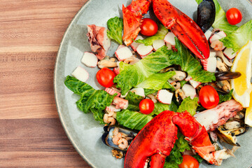 Mix of salad with seafood on plate, top view