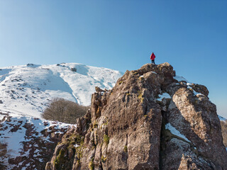 Mountaineer on top of a rock contemplating the summit