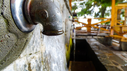 Macro photo of a running water from a tap up in the mountains.