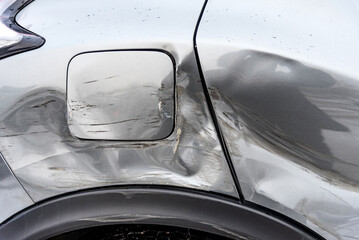 Silver car after the accident, broken door, fender and fuel tank close-up. Car accident close-up. A...