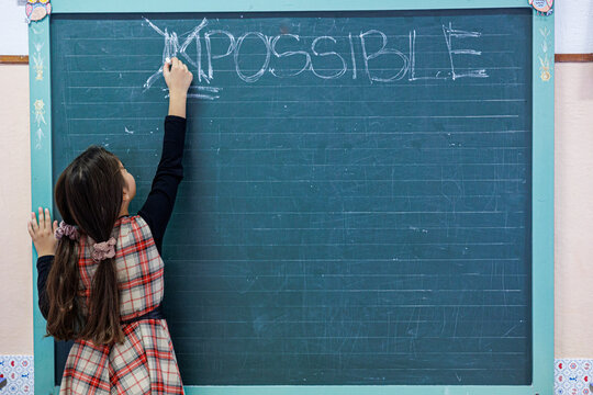 Studentessa cancella con un gesso la parola "impossible" scritta su una lavagna