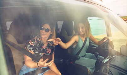 Happy female friends looking landscape through window while traveling in caravan