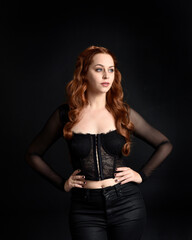 close up portrait of beautiful woman with long red hair wearing sheer corset top. variety of facial expressions,  Isolated on dark studio background with moody silhouette lighting.
