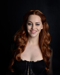 Naklejka premium close up portrait of beautiful woman with long red hair wearing sheer corset top. variety of facial expressions, Isolated on dark studio background with moody silhouette lighting.