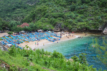 Fototapeta na wymiar Top view high angle of Human activity on the beachside at Gesing Beach, Gunungkidul, Yogyakarta. Afternoon And cloudy weather. Fisherman Village with fishing boat at beach.