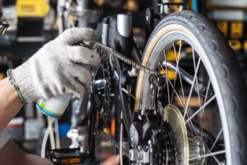 mechanic repairing bicycle, chain lube spray for folding bicycle working in workshop , Bicycle...