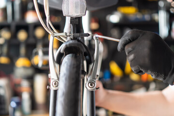 Technician makes adjustments to brake on a folding bicycle working in workshop , Bicycle Repair and maintenance concept