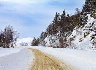 A frosty winter morning in a mountainous area, a snow-covered road is the only way out of snow...