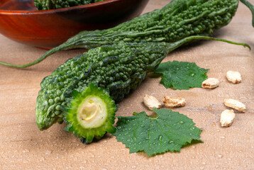 Closeup of fresh bitter gourd with cut slice isolated on wooden background.