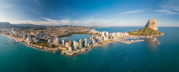 Drone panoramic view of high-rise buildings in Calpe city and Les Salines salt lake.