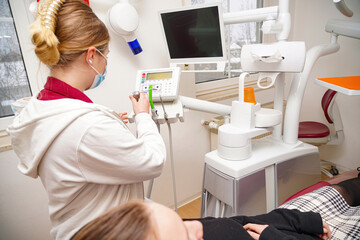 The dentist prepares for work and sets up the remote control for examining teeth.