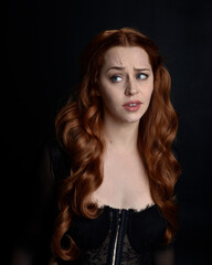 close up portrait of beautiful woman with long red hair wearing sheer corset top. variety of facial...