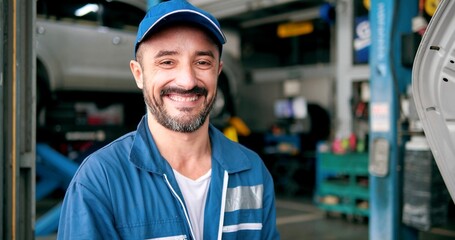 Smiling face of Caucasian man car mechanic standing looking at camera at autocar