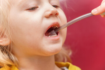 The girl is sitting on a dental chair, the doctor performs various manipulations in the child's...