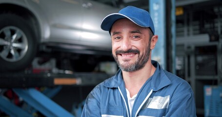 Smiling face of Caucasian man car mechanic standing looking at camera at autocar