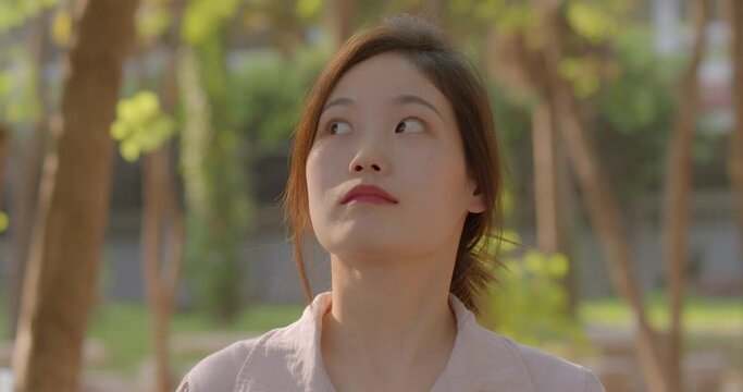 (Slow motion)A happy smiling Asian woman who is a Chinese teacher and teaches Chinese language in a secondary school of Thailand, walking in the school park in the evening after school.