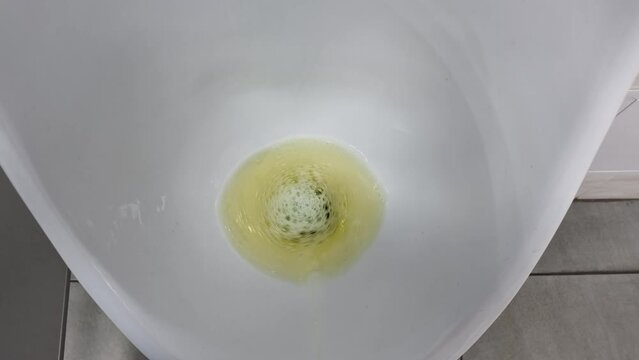 a stream of urine in a toilet bowl. a man pees in the toilet.