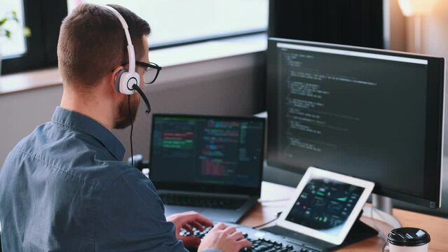 Programmer is working in the modern office. Sitting by computer.