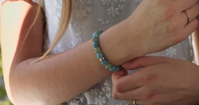 Anonymous high class caucasian woman adjusting luxurious gem beaded bracelet, slow motion