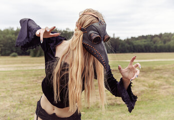 Intriguing portrait of woman in plague mask with forest background.