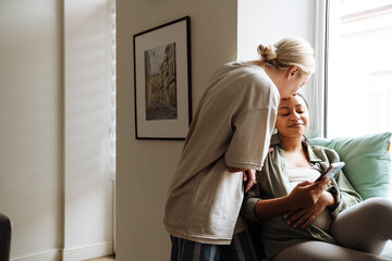 Young woman kissing her pregnant wife while spending time together