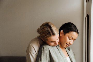 Obraz premium Cheerful lesbian couple hugging while standing together at home