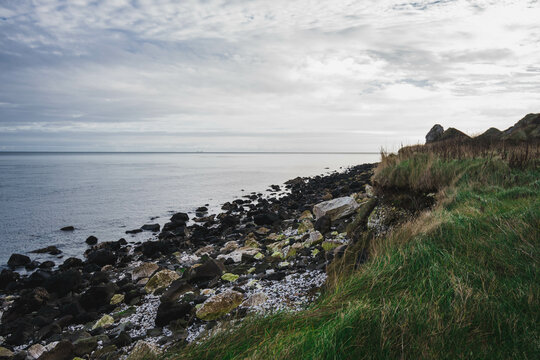 Path Glenarm Coastal Path, south of the village of Glenarm, in Northern Ireland, with beach, boulders and ocean