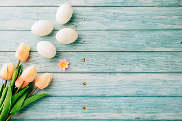 Happy Easter Day Concept. Top view of holiday banner background design white easter eggs and spring tulip flowers on blue wooden background with empty copy space, celebration greeting card