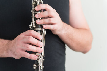Man in black shirt holds clarinet. Horizontal photo of the musician