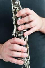 Man in black shirt holds clarinet. Vertical photo of the musician