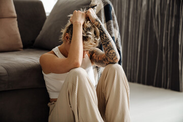 Young woman touching her head while sitting on floor