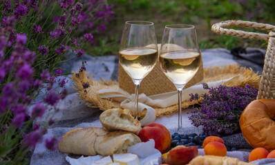wine, fruits, berries, cheese, glasses picnic in lavender field. Selective focus