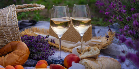 wine, fruits, berries, cheese, glasses picnic in lavender field. Selective focus