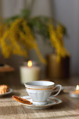 Scented candles, chocolate, cookies, cup of tea, books, e-reader, glasses and flowers on the table. Hygge at home. Selective focus.