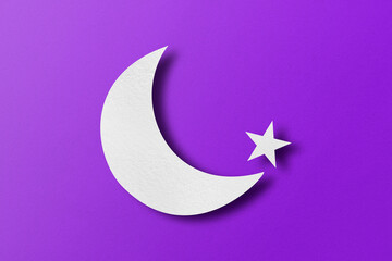 White paper cut into crescent shapes and stars set on purple paper background.